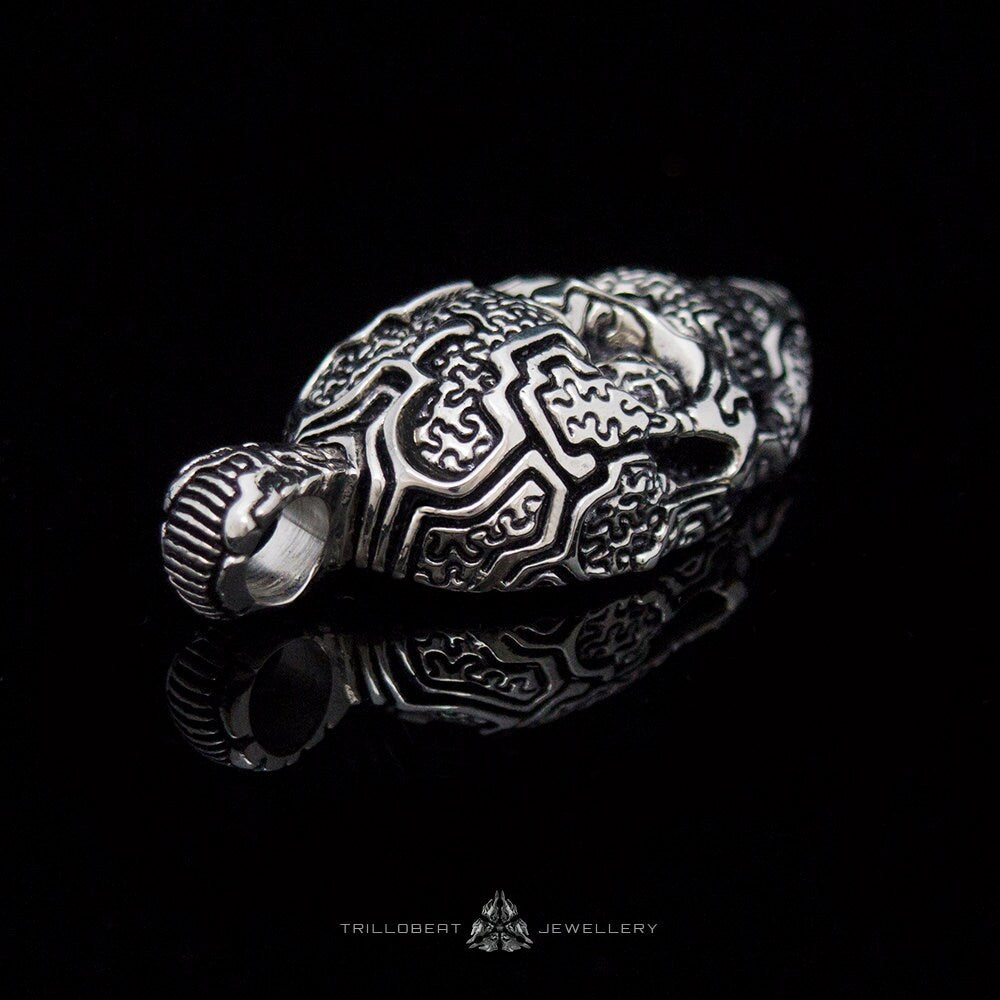 Handmade engraved skull pendant displayed on dark background