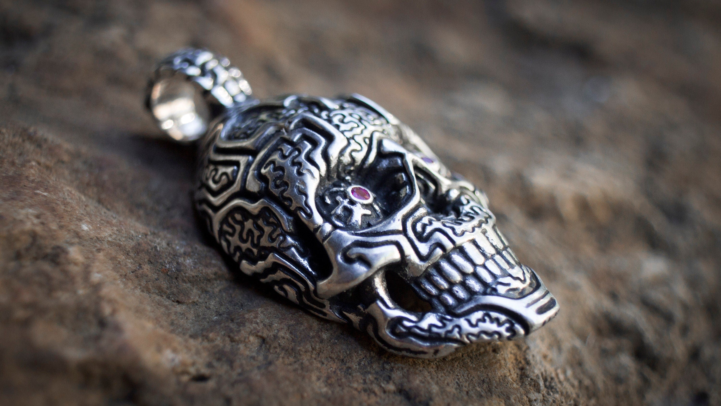 Side view of handmade silver skull pendant with dark details