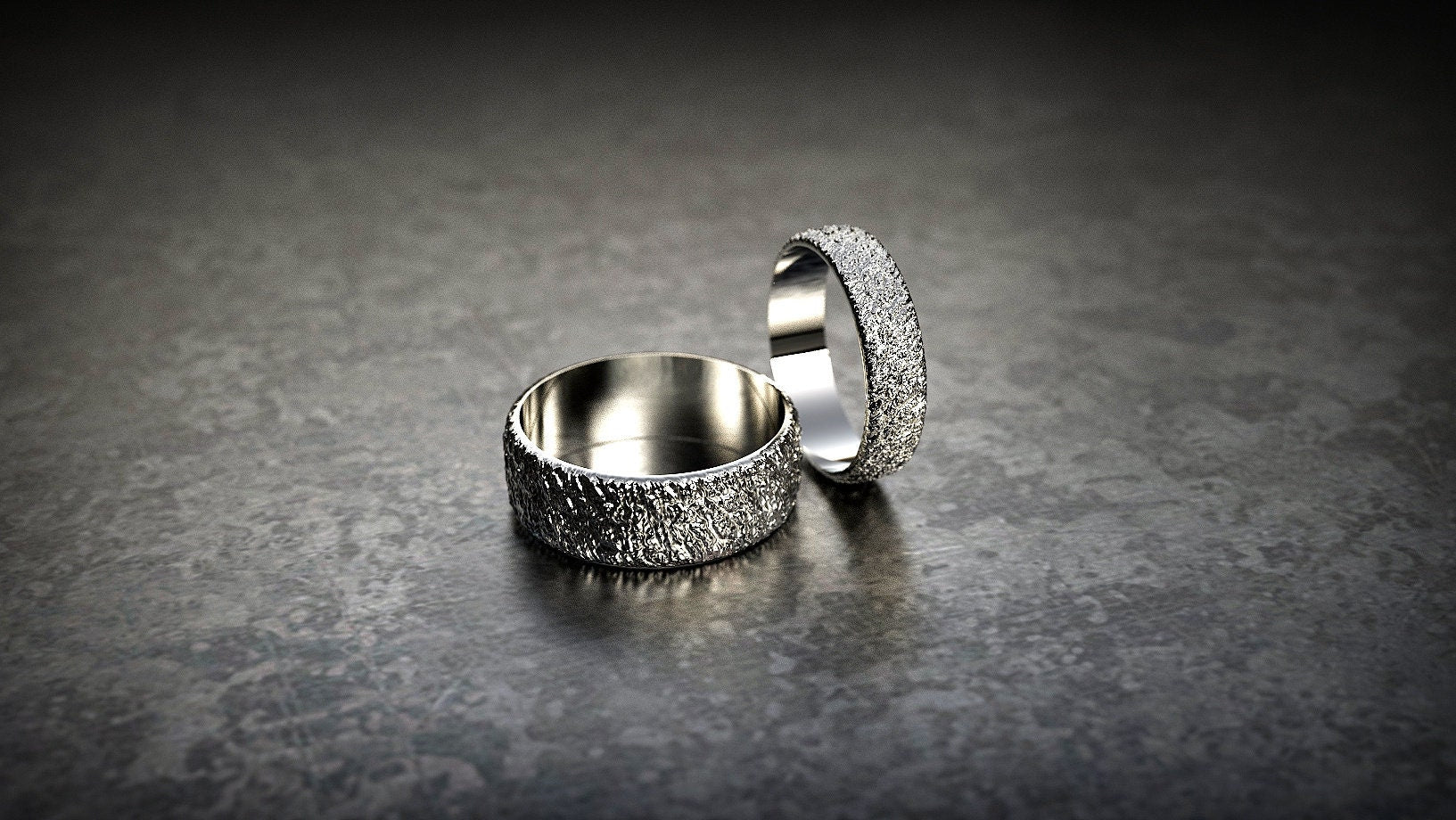 Gold tree-inspired wedding bands on dark background