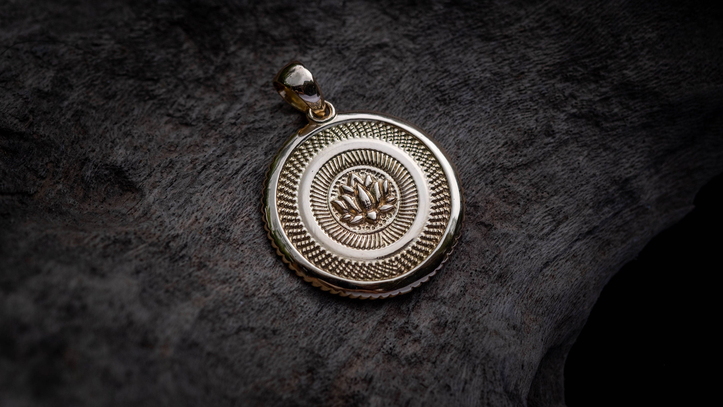 Gold Buddhist pendant displayed on dark background