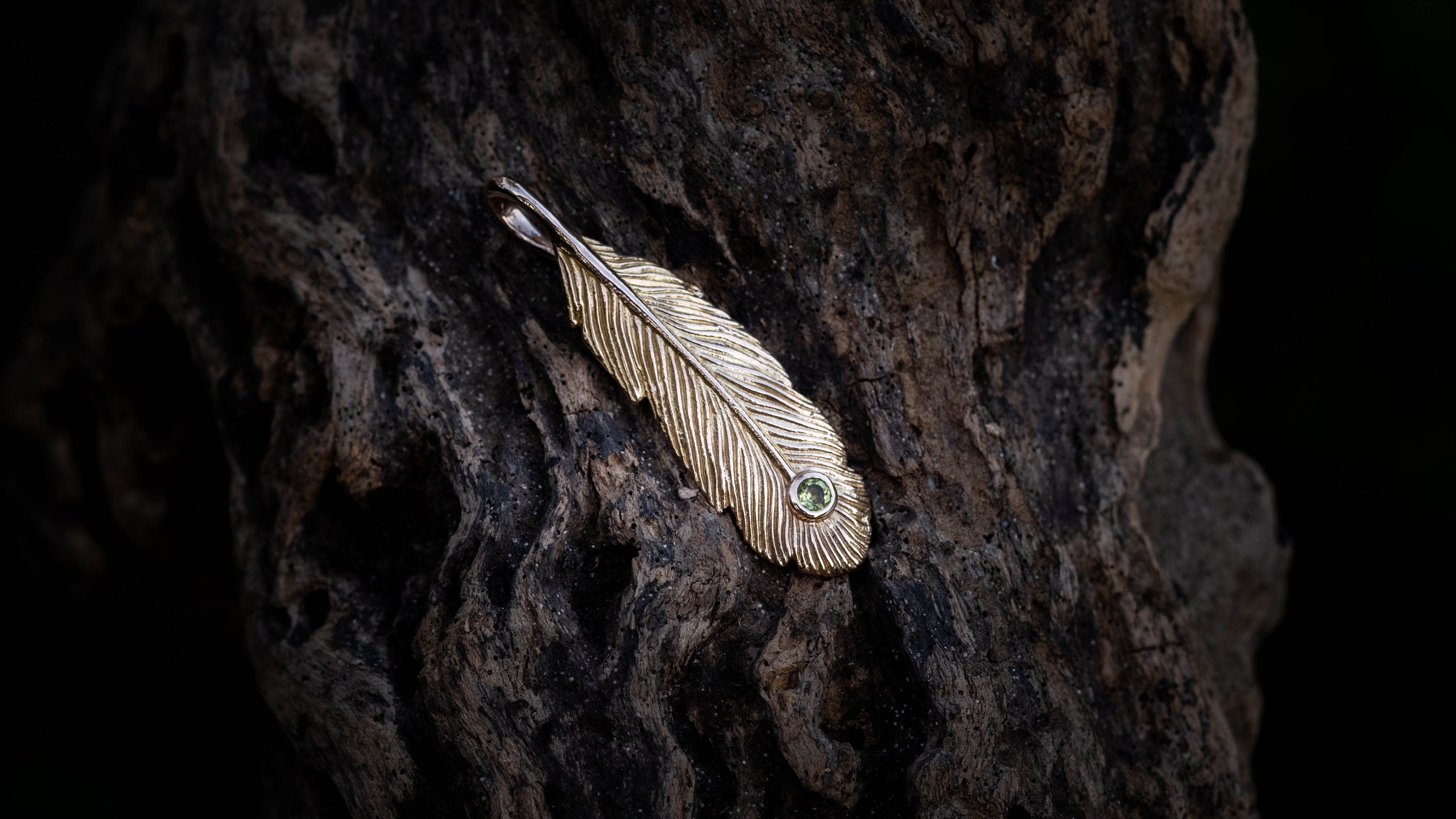 Side view of handmade gold feather necklace with gemstone