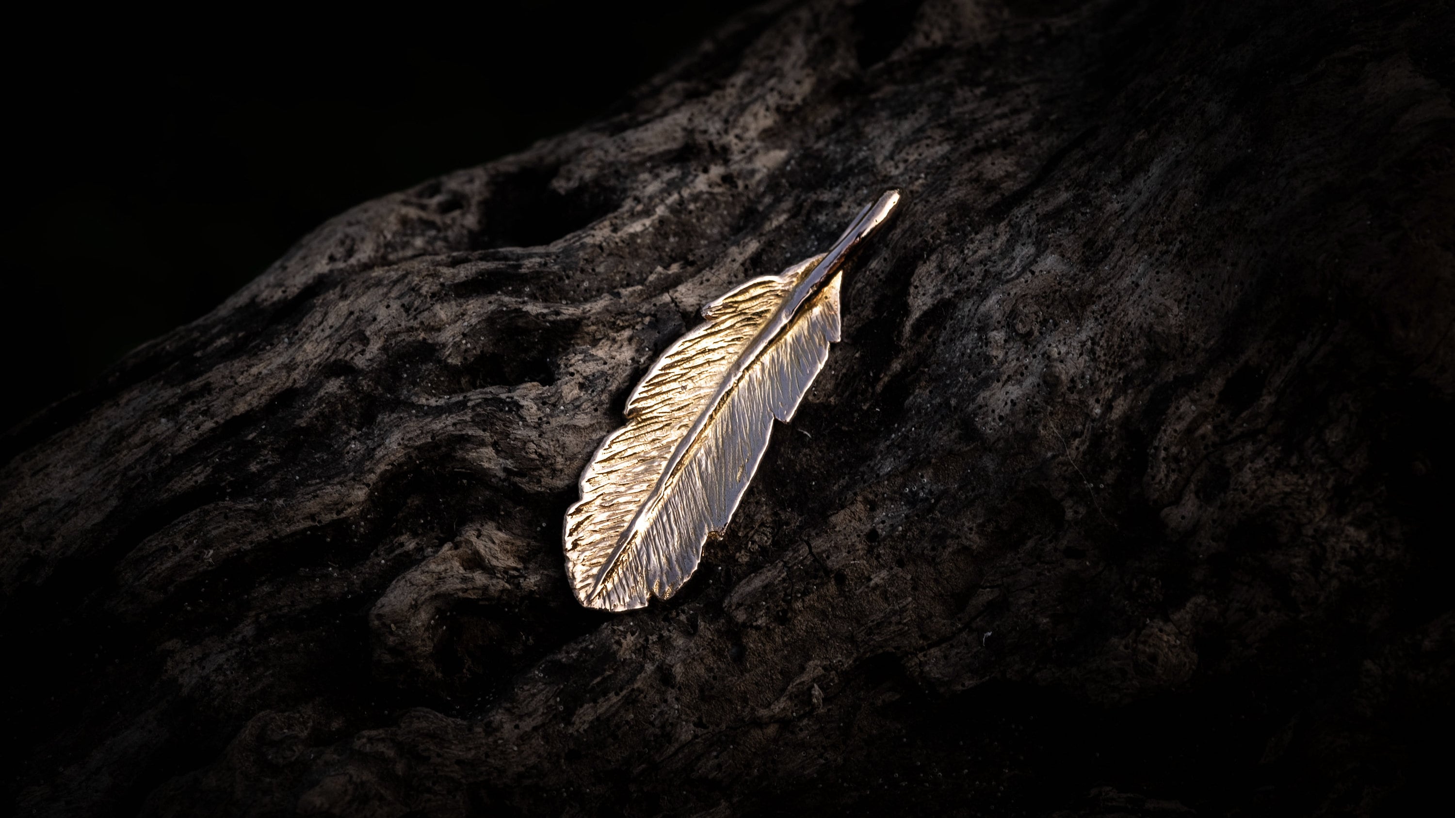 Gold feather pendant photographed as nature-inspired jewelry