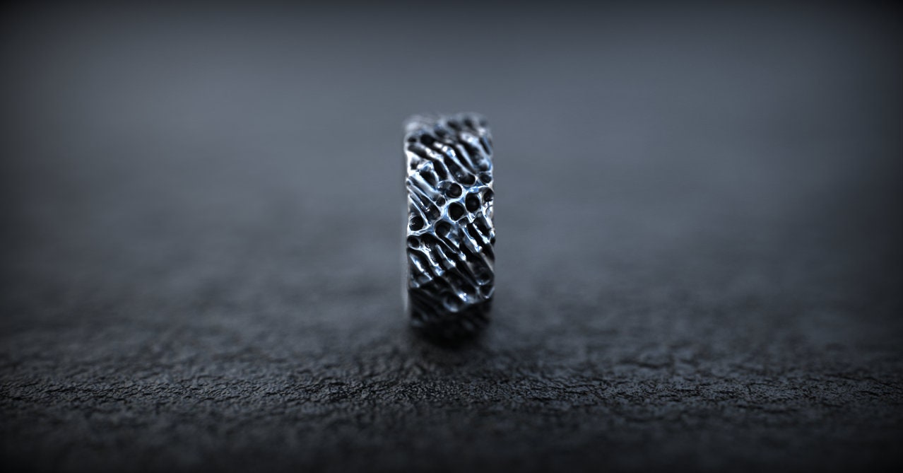 Biomechanical silver engagement ring displayed on dark background